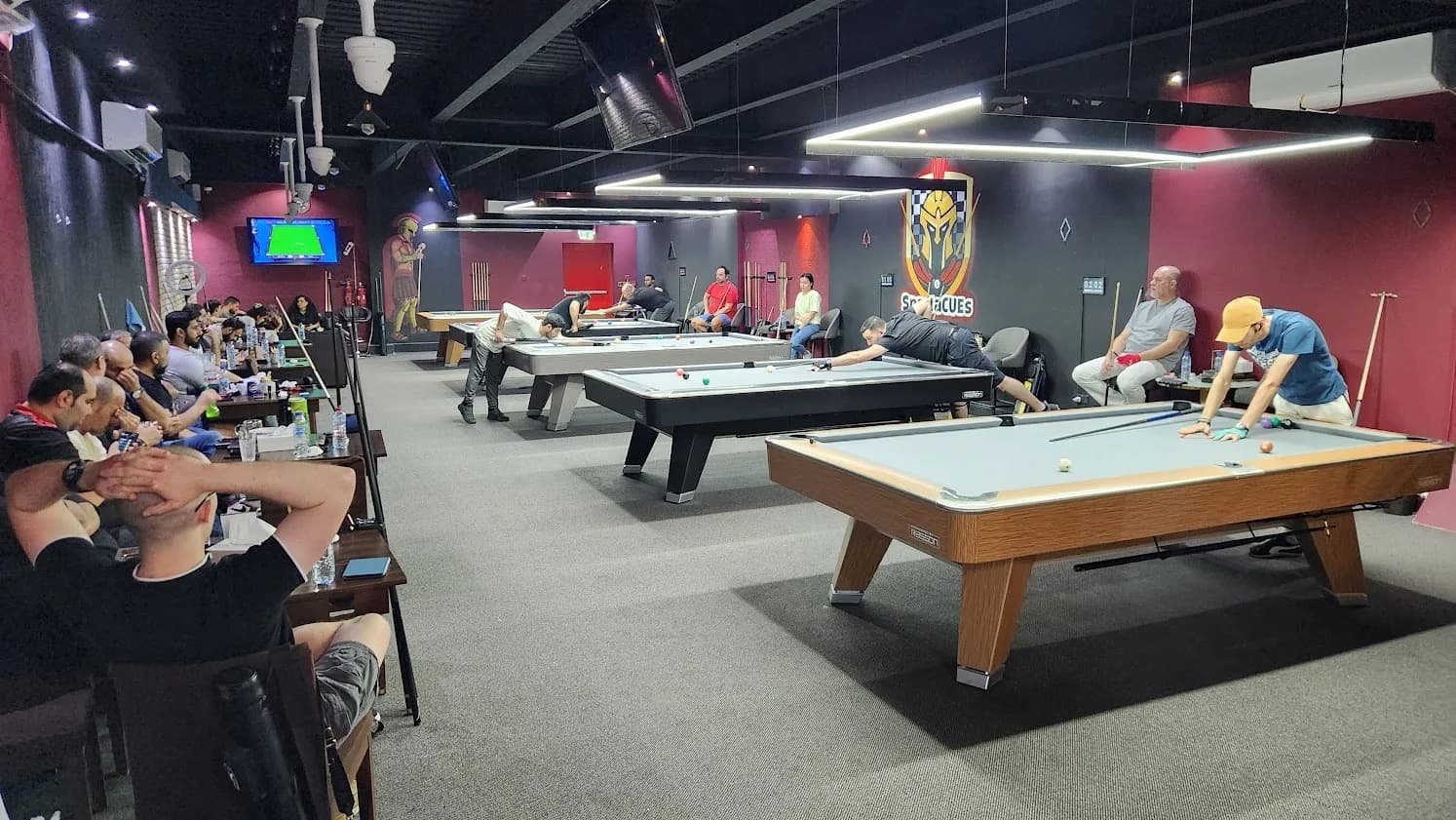 The billiard room at Spartacues, tables under low lamps
